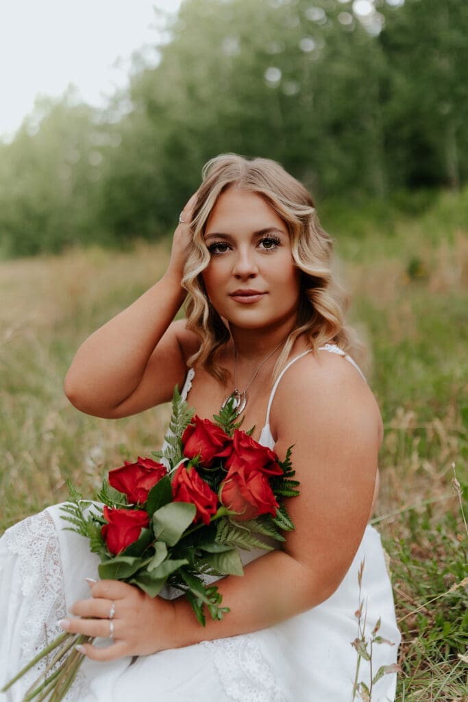 Senior portrait showcasing soft natural lighting and a relaxed outdoor vibe, holding red roses.