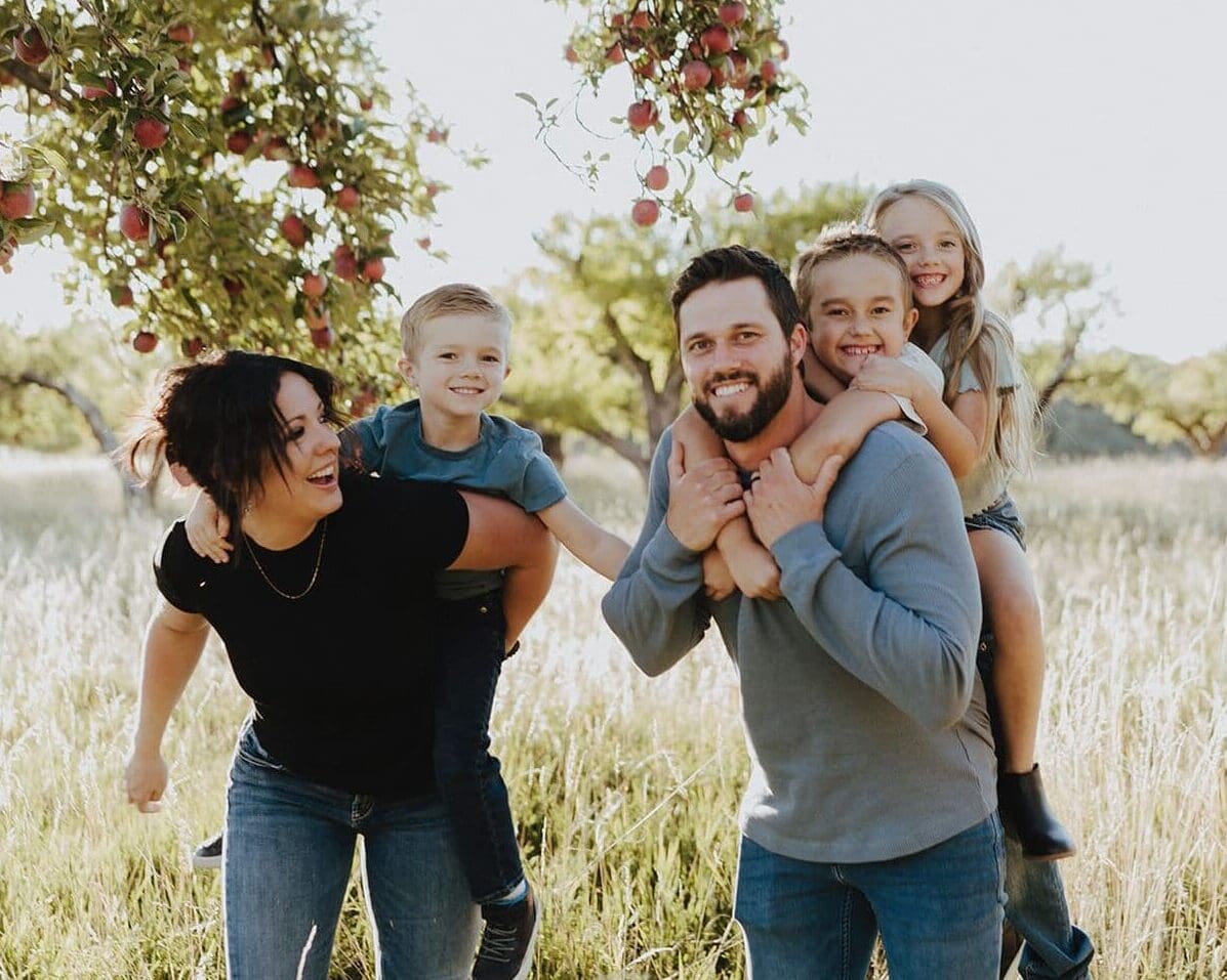 Outdoor family photos in apple orchard. Family is loving and playful having fun and picking apples